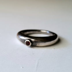 slim rounded band tapered to a narrow base. ring is set with a single round pink rhodalite garnet in tube setting